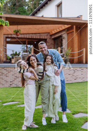 Beautfiul young family standing in front their family home, enjoying together time. 111976901