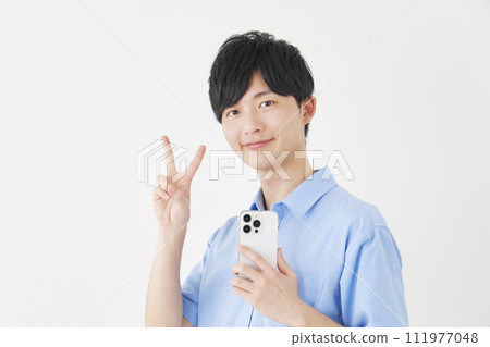 A man holding a smartphone and making a peace sign, white background 111977048