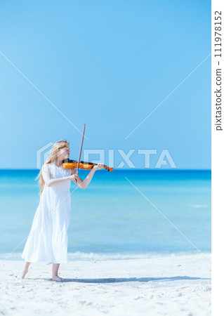teenager girl in dress on ocean shore enjoying playing 111978152