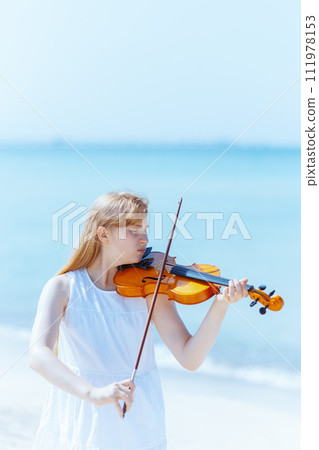 modern teenage girl in light dress enjoying playing on seacoast 111978153