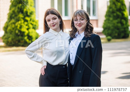 Portrait of two high school girls against the backdrop of the school. 111978737