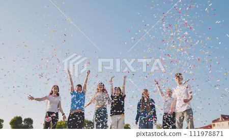 Friends toss colorful paper confetti from their hands. 111978871