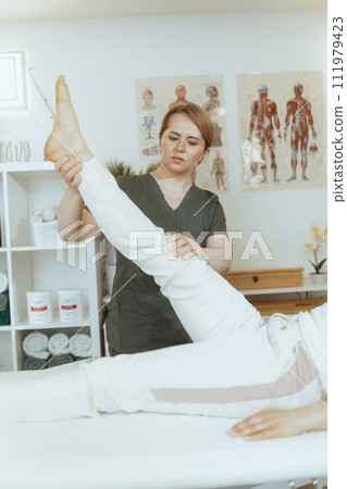 pensive female therapist in massage cabinet doing checkup pensive female therapist in massage cabinet doing checkup 111979423