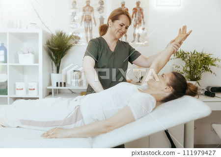 female therapist in massage cabinet conducting examination female therapist in massage cabinet conducting examination 111979427