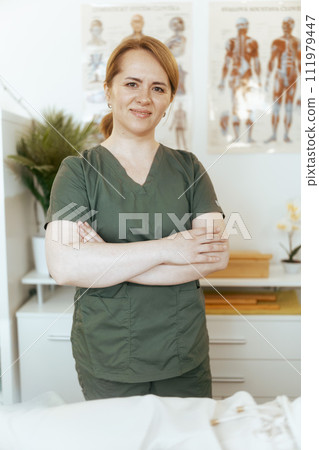 Portrait of happy female massage therapist in massage cabinet 111979447