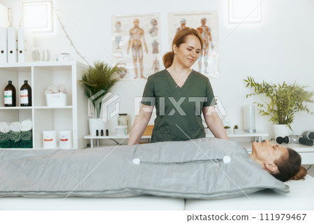 smiling female medical massage therapist in massage cabinet 111979467