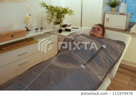 woman doing whiskey swaddling procedure in thermal blanket 111979476