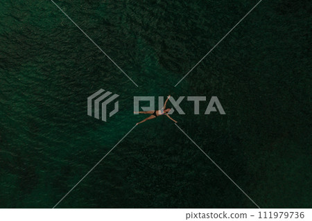 Aerial top nature view above green turquoise Adriatic sea in Albania. young woman swimming alone 111979736