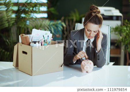 woman worker in green office putting coin into piggy bank 111979854