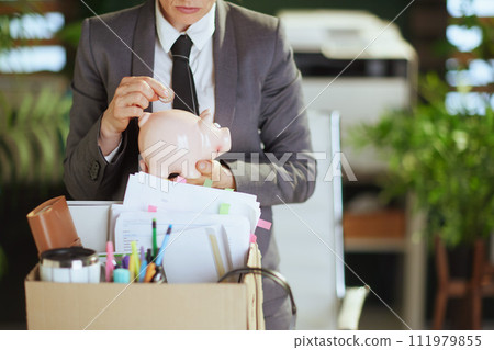 Modern woman worker in green office putting coin into piggy bank 111979855