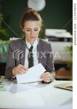 pensive woman employee in green office opening letter 111979859