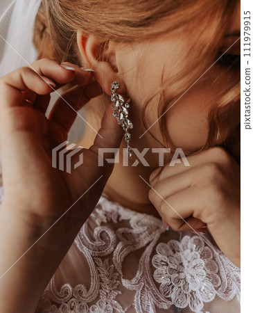 girl puts on big massive voluminous precious earrings in teams and stones girl puts on big massive voluminous precious earrings in teams and stones 111979915