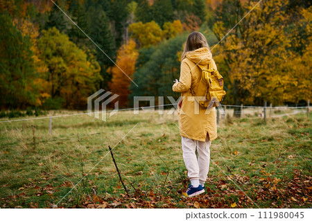 Woman in Yellow Coat Near Autumn Forest 111980045