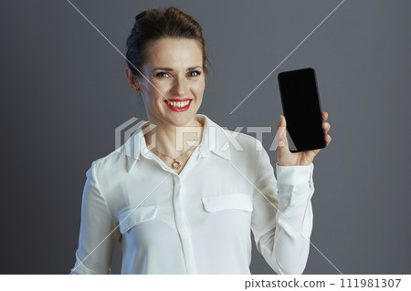 woman employee showing smartphone blank screen against grey 111981307