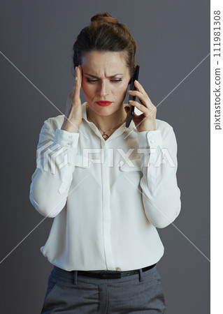 stressed female employee talking on phone isolated on grey 111981308
