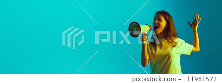 Banner. Emotional young lady shouting to megaphone in neon light against gradient blue background with negative space to insert text. Banner. Emotional young lady shouting to megaphone in neon light against gradient blue background with negative space to insert text. 111981572