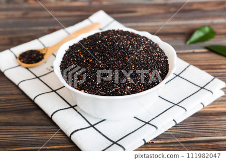 quinoa seeds in bowl and spoon on colored background. Healthy kinwa in small bowl. Healthy superfood quinoa seeds in bowl and spoon on colored background. Healthy kinwa in small bowl. Healthy superfood 111982047
