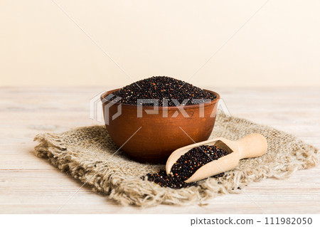 quinoa seeds in bowl and spoon on colored background. Healthy kinwa in small bowl. Healthy superfood quinoa seeds in bowl and spoon on colored background. Healthy kinwa in small bowl. Healthy superfood 111982050