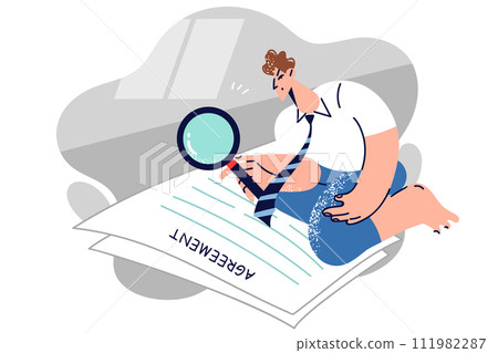 Man lawyer reads large agreement and uses magnifying glass to scrutinize business documents 111982287