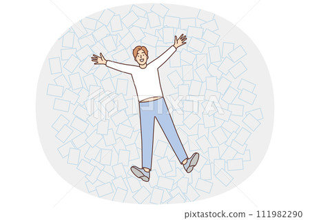 Young man lies among office papers in pose of angel, enjoying rest and not paying attention to mess Young man lies among office papers in pose of angel, enjoying rest and not paying attention to mess 111982290