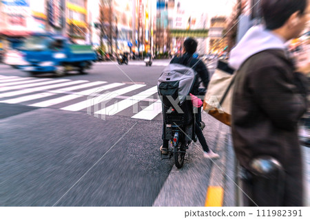 日本東京城市景觀 一輛自行車騎錯了方向...令人驚訝地看到後面有一個孩子...冠狀病毒留下了什麼... = 秋葉原 111982391