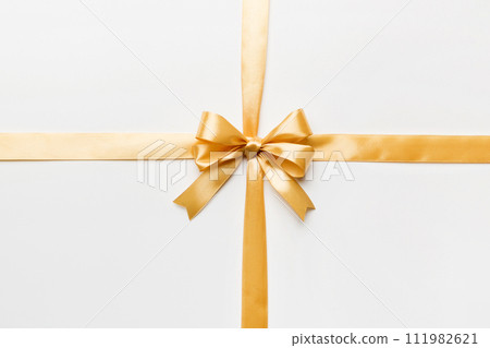 Top view of gold ribbon rolled and yellow bow isolated on colored background. Flat lay with copy space 111982621