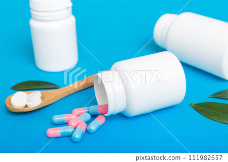different drugs and health supplement pills poured from a medicine bottle health care and medical top view on colored background 111982657