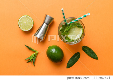 Caipirinha, Mojito cocktail, vodka or soda drink with lime, mint and straw on table background. Refreshing beverage with mint and lime in glass top view flat lay Caipirinha, Mojito cocktail, vodka or soda drink with lime, mint and straw on table background. Refreshing beverage with mint and lime in glass top view flat lay 111982671