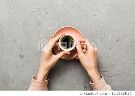Minimalistic style woman hand holding a cup of coffee on Colored background. Flat lay, top view cappuccino cup. Empty place for text, copy space. Coffee addiction. Top view, flat lay 111982685