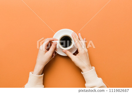 Minimalistic style woman hand holding a cup of coffee on Colored background. Flat lay, top view cappuccino cup. Empty place for text, copy space. Coffee addiction. Top view, flat lay Minimalistic style woman hand holding a cup of coffee on Colored background. Flat lay, top view cappuccino cup. Empty place for text, copy space. Coffee addiction. Top view, flat lay 111982687