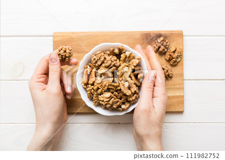 Woman hands holding a wooden bowl with walnut nuts. Healthy food and snack. Vegetarian snacks of different nuts Woman hands holding a wooden bowl with walnut nuts. Healthy food and snack. Vegetarian snacks of different nuts 111982752