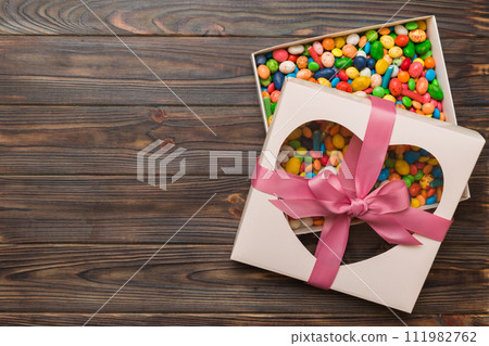 Box with sweet chocolate candies on color background, Various candy sweets. Valentines day gift box. Top view flat lay with copy space 111982762