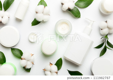Organic cosmetic products with cotton flower and green leaves on white background. Flat lay 111982787