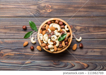 Assortment of nuts in wooden bowl on colored table. Cashew, hazelnuts, walnuts, almonds. Mix of nuts Top view with copy space 111982789