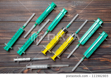 Top view of many syringes prepared for injection at wooden background. Treatment concept with copy space Top view of many syringes prepared for injection at wooden background. Treatment concept with copy space 111982803