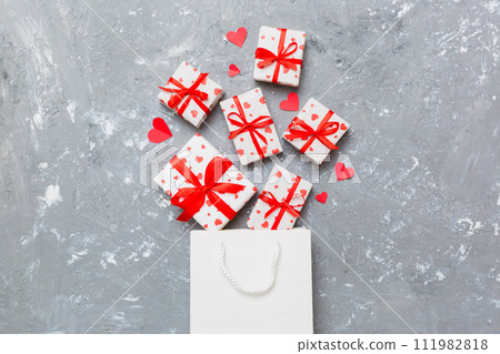Gift boxes pop out from paper bag top view on colored background. bag packing handmade boxes fall out Concept of holidays, shopping, sale, discounts. Top view, flat lay Gift boxes pop out from paper bag top view on colored background. bag packing handmade boxes fall out Concept of holidays, shopping, sale, discounts. Top view, flat lay 111982818
