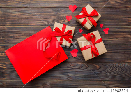 Gift boxes pop out from paper bag top view on colored background. bag packing handmade boxes fall out Concept of holidays, shopping, sale, discounts. Top view, flat lay Gift boxes pop out from paper bag top view on colored background. bag packing handmade boxes fall out Concept of holidays, shopping, sale, discounts. Top view, flat lay 111982824