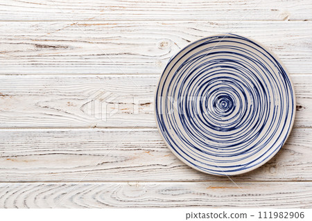 Top view of empty colorful plate on wooden background. Empty space for your design Top view of empty colorful plate on wooden background. Empty space for your design 111982906