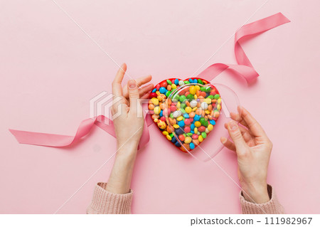 Female hands with delicious candies in box on color background Female hands with delicious candies in box on color background 111982967