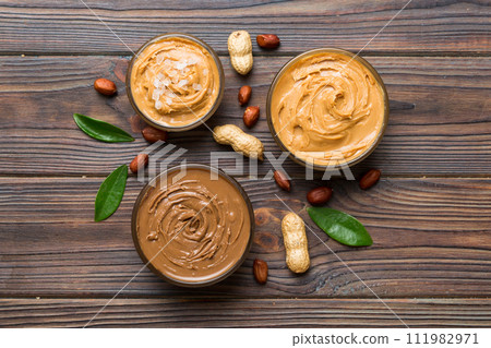 Glass jar with peanut butter on table background, top view space for text and close up 111982971