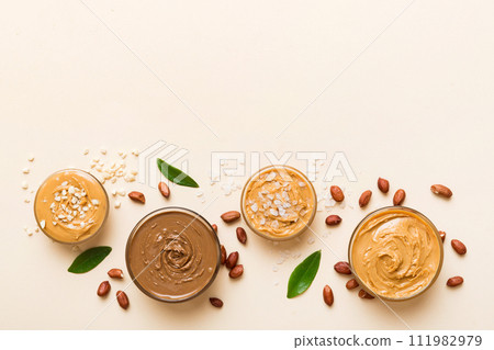 Glass jar with peanut butter on table background, top view space for text and close up 111982979
