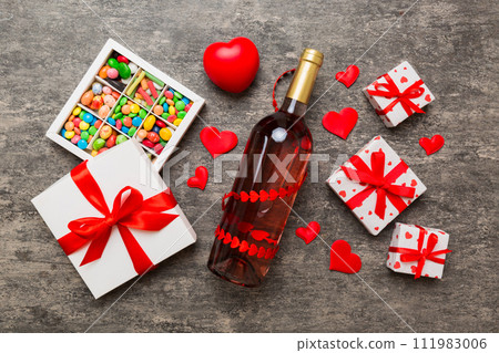 Bottle of red wine on colored background for Valentine Day with gift and chocolate. Heart shaped with gift box of chocolates top view with copy space Bottle of red wine on colored background for Valentine Day with gift and chocolate. Heart shaped with gift box of chocolates top view with copy space 111983006