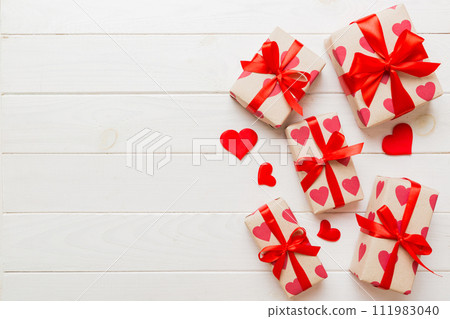Top view photo of valentine day decorations gift box with red ribbon bow on colored background. Holiday gift boxes with top view 111983040