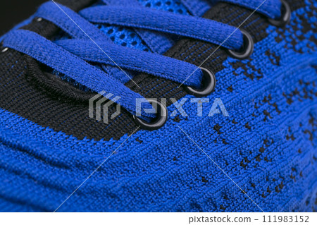 Part of a blue sneaker made of fabric with laces. A fragment of sports shoes. 111983152
