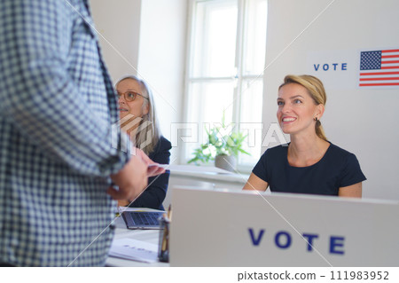 Member of electoral commission in polling place on election day, usa elections. Handing ballot. Member of electoral commission in polling place on election day, usa elections. Handing ballot. 111983952