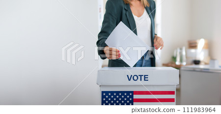 Unrecognizable woman putting her vote in the ballot box, usa elections. Banner with copy space. Unrecognizable woman putting her vote in the ballot box, usa elections. Banner with copy space. 111983964