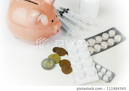 The blue piggy bank is surrounded by various medicines and euro coins 111984343