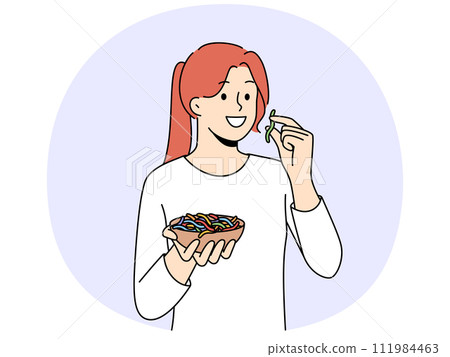 Smiling girl eating colorful gummy worms 111984463