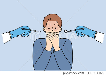 Man suffering from dentophobia closes mouth and stands near hands with dental devices 111984468