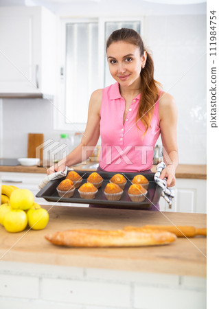 Woman taking out just baked cupcakes. Woman cooking cakes at home 111984754